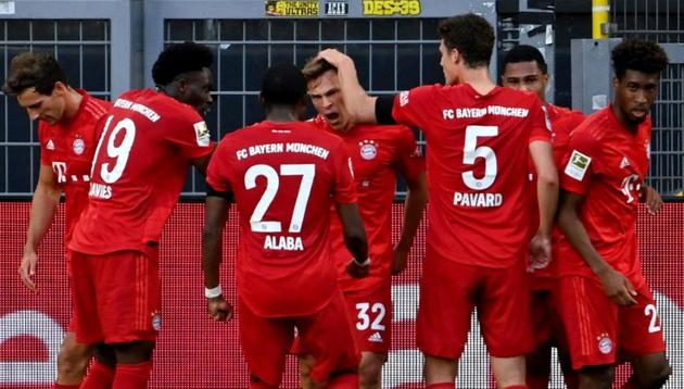 Le milieu du Bayern Munich, Joshua Kimmich (c), félicité par ses coéquipiers après son  but à Dortmund, en Bundesliga, le 26 mai 2020 [Federico GAMBARINI / POOL/AFP]