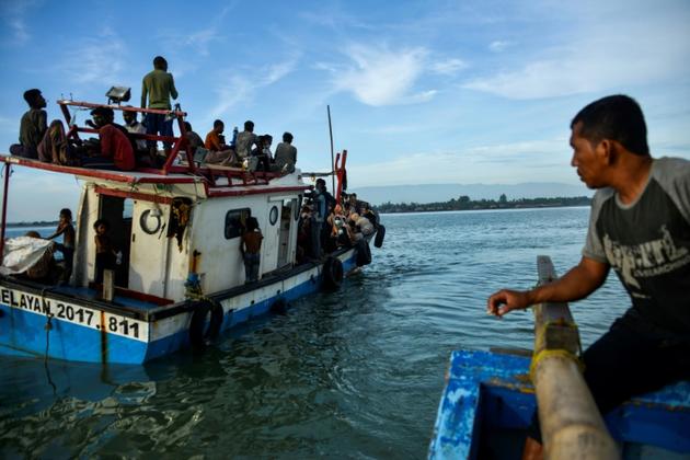 Un pêcheur du village de Lancok, dans la région d'Aceh en Indonésie, vient aider, le 25 juin 2020, des réfugiés rohingyas à débarquer, après une longue dérive en mer [CHAIDEER MAHYUDDIN / AFP]