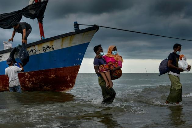Des pêcheurs du village de Lancok, dans la région d'Aceh en Indonésie, le 25 juin 2020, aident des réfugiés rohingyas à débarquer, après une longue dérive en mer [CHAIDEER MAHYUDDIN / AFP]