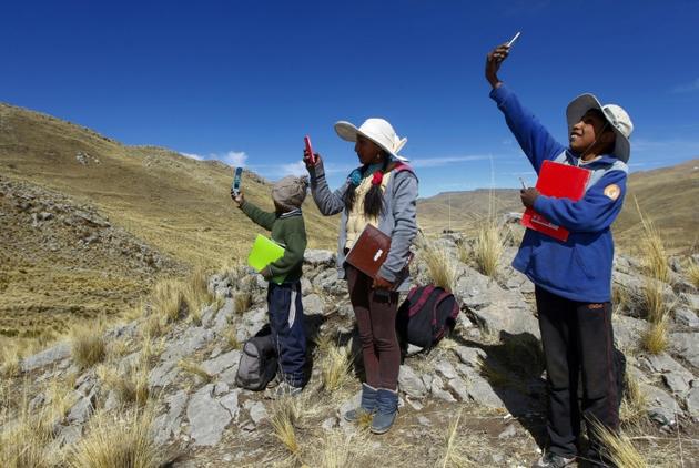Des enfants péruviens à la recherche de signal au sommet d'une colline pour suivre leurs cours à distance dans le district de Manazo, dans les Andes péruviennes le 24 juillet 2020 [Carlos MAMANI / AFP]