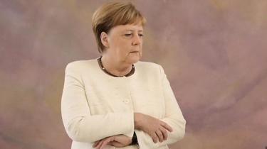 Angela Merkel a tenté de croiser les bras pour contrôler sa crise de tremblements, qui a duré environ deux minutes selon un photographe présent sur place. 